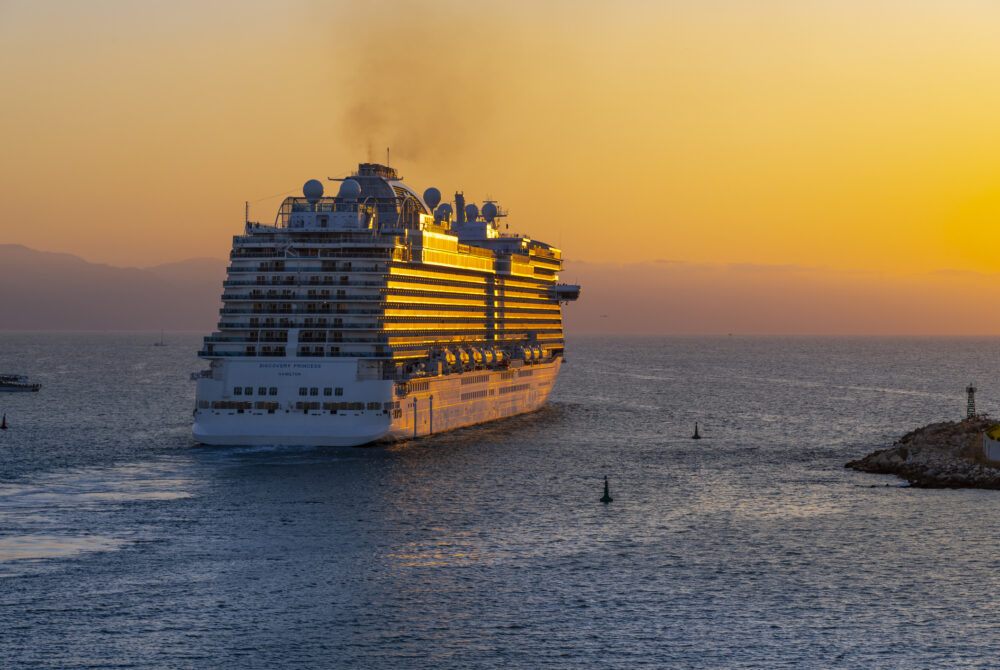 Sunset evening view of a large cruise ship as it exits the cruise port of Puerto Vallarta, Mexico.