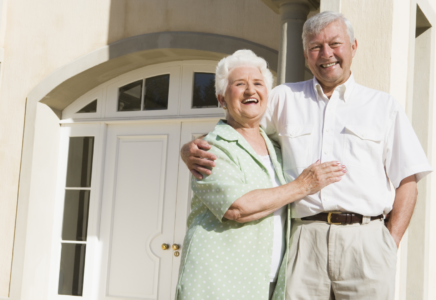Pensioner couple smiling outside their home