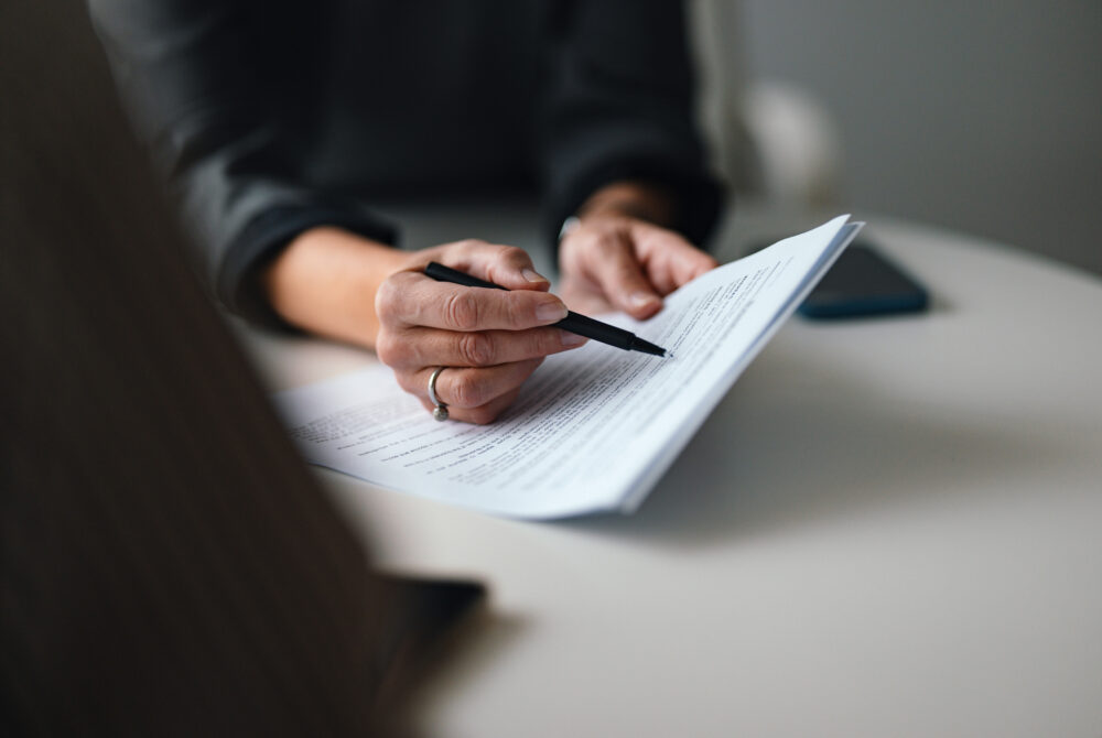 Close-Up of a Person Reviewing and Discussing Document in Office Environment