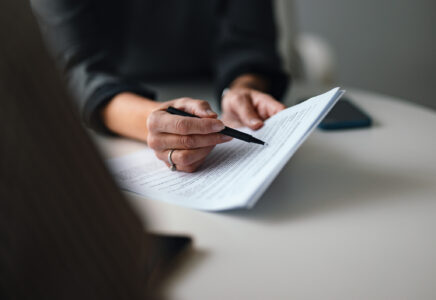 Close-Up of a Person Reviewing and Discussing Document in Office Environment