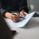 Close-Up of a Person Reviewing and Discussing Document in Office Environment